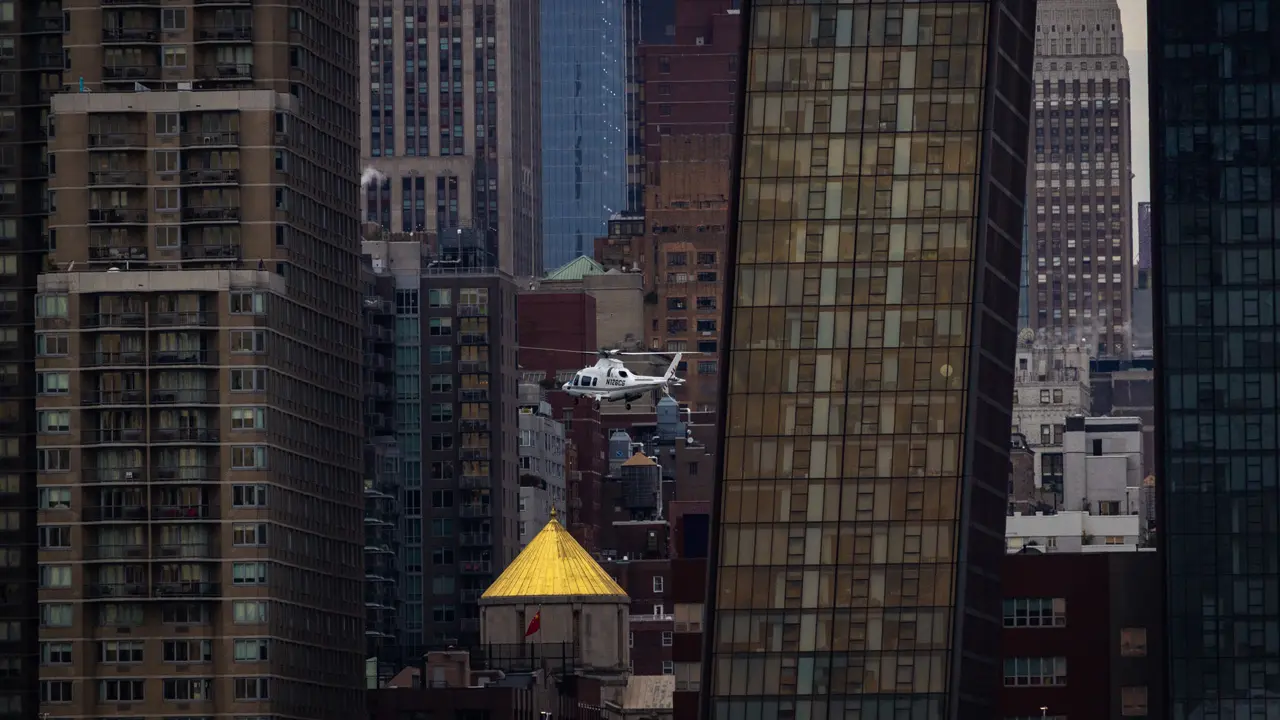 A helicopter taking off, juxtaposed against buildings.